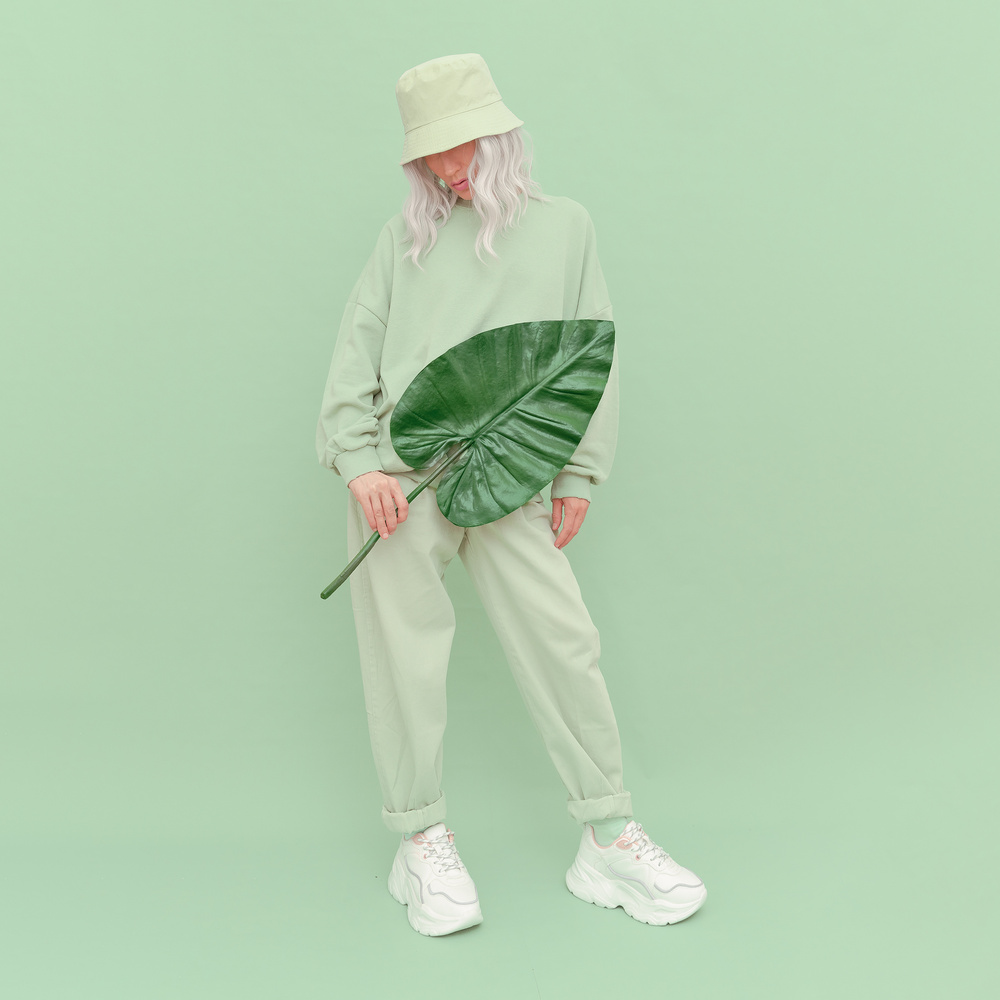 Young Woman in a Green Outfit Posing with a Leaf